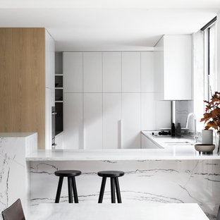 Inspiration for a contemporary u-shaped kitchen in Melbourne with a double-bowl sink, flat-panel cabinets, white cabinets, white splashback, stone slab splashback, a peninsula and white benchtop.