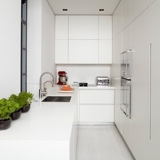 Photo of a modern l-shaped separate kitchen in London with an undermount sink, flat-panel cabinets, white cabinets, panelled appliances and white splashback.
