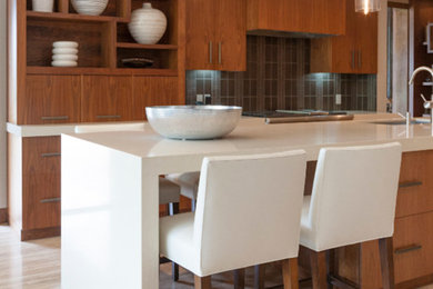 Cette photo montre une cuisine ouverte linéaire tendance en bois brun avec un placard à porte plane, un plan de travail en quartz, une crédence grise, un sol en carrelage de porcelaine, îlot et un sol beige.