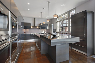 Example of a large minimalist u-shaped concrete floor and brown floor enclosed kitchen design in Los Angeles with flat-panel cabinets, gray cabinets, quartz countertops, paneled appliances and an island