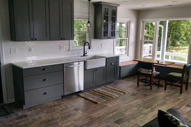 Open concept kitchen - mid-sized contemporary single-wall medium tone wood floor and brown floor open concept kitchen idea in Richmond with a farmhouse sink, shaker cabinets, gray cabinets, quartz countertops, white backsplash, subway tile backsplash and no island