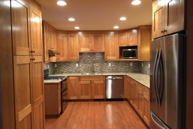 Enclosed kitchen - mid-sized contemporary u-shaped medium tone wood floor enclosed kitchen idea in Other with a double-bowl sink, raised-panel cabinets, medium tone wood cabinets, granite countertops, gray backsplash, ceramic backsplash, stainless steel appliances and no island
