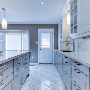 Mid-sized transitional l-shaped separate kitchen in Toronto with an undermount sink, raised-panel cabinets, white cabinets, quartz benchtops, beige splashback, porcelain splashback, stainless steel appliances, ceramic floors and with island.