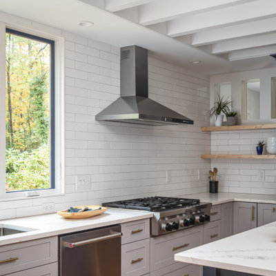 Inspiration for a mid-sized transitional u-shaped medium tone wood floor and brown floor open concept kitchen remodel in Raleigh with an undermount sink, recessed-panel cabinets, blue cabinets, quartzite countertops, white backsplash, subway tile backsplash, stainless steel appliances, an island and white countertops