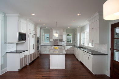 Example of a large minimalist u-shaped dark wood floor kitchen design in Chicago with an undermount sink, recessed-panel cabinets, white cabinets, granite countertops, white backsplash, subway tile backsplash, white appliances and an island