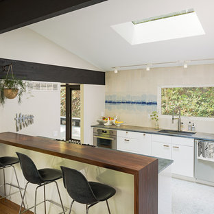 Midcentury single-wall open plan kitchen in Philadelphia with an undermount sink, flat-panel cabinets, white cabinets, wood benchtops, beige splashback, ceramic splashback, stainless steel appliances, marble floors, with island and white floor.