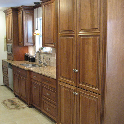 Example of a mid-sized transitional galley ceramic tile open concept kitchen design in Jacksonville with an undermount sink, raised-panel cabinets, dark wood cabinets, granite countertops, beige backsplash, stone tile backsplash, stainless steel appliances and no island