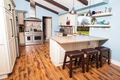 Mid-sized transitional u-shaped eat-in kitchen photo in Boise with an undermount sink, shaker cabinets, yellow cabinets, quartz countertops, brown backsplash, stone tile backsplash, stainless steel appliances and a peninsula