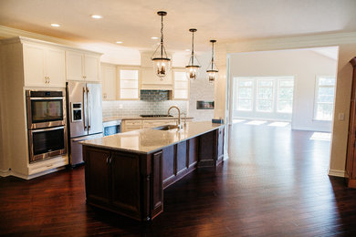 Inspiration for a large timeless dark wood floor eat-in kitchen remodel in Columbus with an undermount sink, white cabinets, granite countertops, blue backsplash, subway tile backsplash, stainless steel appliances and an island