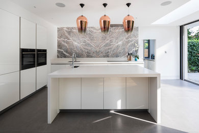 Design ideas for a contemporary l-shaped open plan kitchen in London with a submerged sink, flat-panel cabinets, white cabinets, composite countertops, marble splashback, stainless steel appliances, ceramic flooring, an island, grey floors and grey splashback.