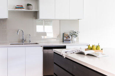 Exempel på ett mellanstort modernt flerfärgad flerfärgat kök, med en undermonterad diskho, släta luckor, skåp i mörkt trä, bänkskiva i kvarts, grått stänkskydd, glaspanel som stänkskydd, rostfria vitvaror, mellanmörkt trägolv, en köksö och brunt golv