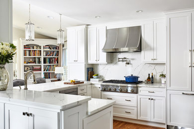 Diseño de cocina clásica renovada de tamaño medio con puertas de armario blancas, salpicadero blanco, electrodomésticos de acero inoxidable, suelo de madera en tonos medios y encimeras blancas