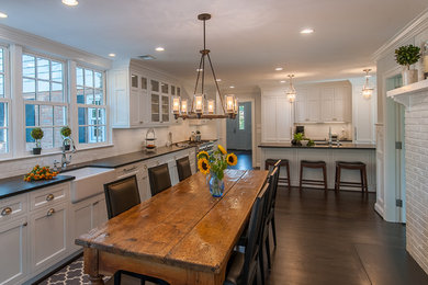 Inspiration for a large timeless l-shaped dark wood floor and brown floor open concept kitchen remodel in DC Metro with a farmhouse sink, recessed-panel cabinets, white cabinets, quartz countertops, white backsplash, ceramic backsplash, stainless steel appliances and an island