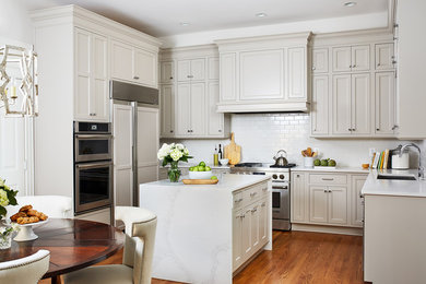 Mid-sized elegant u-shaped medium tone wood floor and orange floor eat-in kitchen photo in DC Metro with beige cabinets, white backsplash, subway tile backsplash, an island, white countertops, an undermount sink, shaker cabinets and paneled appliances