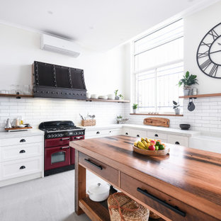 Inspiration for a large country u-shaped open plan kitchen in Sydney with a farmhouse sink, shaker cabinets, white cabinets, quartz benchtops, white splashback, ceramic splashback, coloured appliances, with island, grey floor and grey benchtop.