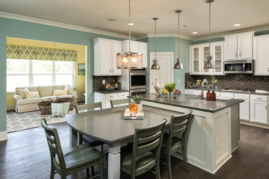 Large transitional u-shaped dark wood floor and brown floor eat-in kitchen photo in Other with a farmhouse sink, recessed-panel cabinets, white cabinets, quartz countertops, gray backsplash, glass tile backsplash, stainless steel appliances and an island