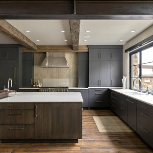 Photo of a large country u-shaped eat-in kitchen in Denver with an undermount sink, flat-panel cabinets, grey cabinets, grey splashback, stainless steel appliances, medium hardwood floors, with island, brown floor and white benchtop.