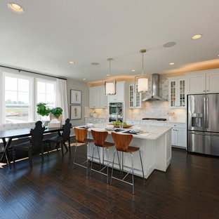 Photo of a large midcentury l-shaped eat-in kitchen in DC Metro with an undermount sink, shaker cabinets, white cabinets, marble benchtops, multi-coloured splashback, subway tile splashback, stainless steel appliances, vinyl floors, with island and brown floor.