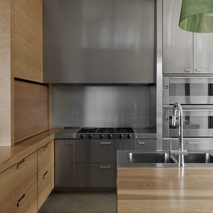 Design ideas for a contemporary l-shaped kitchen in Melbourne with a double-bowl sink, flat-panel cabinets, stainless steel cabinets, wood benchtops, grey splashback, metal splashback, stainless steel appliances, with island, grey floor and brown benchtop.