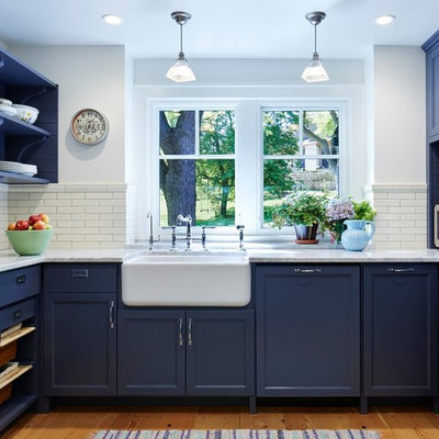 Inspiration for a large timeless u-shaped medium tone wood floor kitchen remodel in Minneapolis with a farmhouse sink, recessed-panel cabinets, blue cabinets, marble countertops, white backsplash, stainless steel appliances and an island