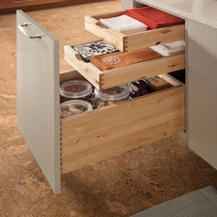 Modelo de cocina de galera, moderna, de tamaño medio, cerrada, con fregadero bajoencimera, armarios con paneles lisos, puertas de armario de madera oscura, encimera de laminado, salpicadero blanco, salpicadero de azulejos de cerámica, electrodomésticos de acero inoxidable, suelo de corcho y una isla