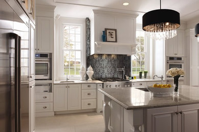 Large trendy l-shaped porcelain tile and beige floor enclosed kitchen photo in Detroit with an undermount sink, raised-panel cabinets, white cabinets, granite countertops, multicolored backsplash, porcelain backsplash, stainless steel appliances and an island
