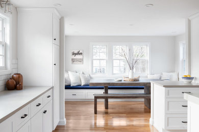 Example of a mid-sized transitional u-shaped light wood floor and beige floor eat-in kitchen design in Boston with an undermount sink, shaker cabinets, white cabinets, quartz countertops, white backsplash, subway tile backsplash, stainless steel appliances, an island and gray countertops