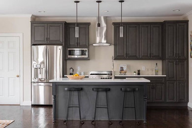 Example of a mid-sized trendy galley dark wood floor and brown floor open concept kitchen design in Boston with a farmhouse sink, raised-panel cabinets, gray cabinets, quartz countertops, beige backsplash, stainless steel appliances and an island
