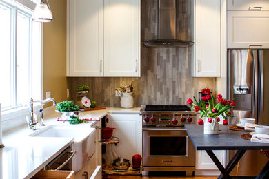 Ejemplo de cocina tradicional con fregadero sobremueble, armarios estilo shaker, puertas de armario blancas, salpicadero verde, electrodomésticos de acero inoxidable y suelo de madera en tonos medios