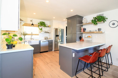 Medium sized contemporary l-shaped kitchen/diner in Los Angeles with shaker cabinets, grey cabinets, engineered stone countertops, white splashback, a breakfast bar and white worktops.