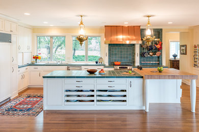 Photo of a large classic l-shaped kitchen/diner in Minneapolis with a submerged sink, shaker cabinets, white cabinets, tile countertops, blue splashback, integrated appliances, medium hardwood flooring, an island, ceramic splashback and turquoise worktops.