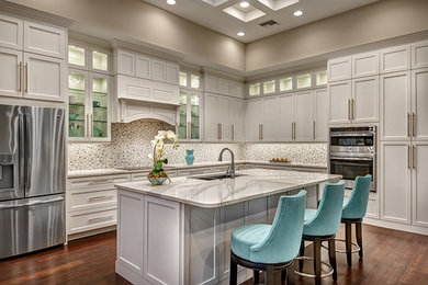 Inspiration for a large transitional l-shaped medium tone wood floor open concept kitchen remodel in Miami with an undermount sink, shaker cabinets, white cabinets, quartz countertops, white backsplash, mosaic tile backsplash, stainless steel appliances and an island