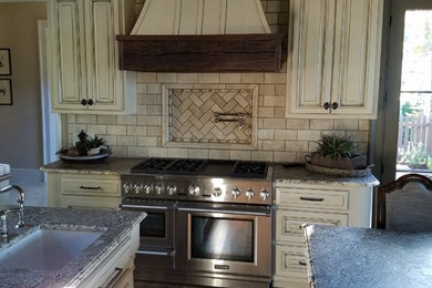 Example of a mid-sized mountain style u-shaped medium tone wood floor and brown floor open concept kitchen design in Other with an undermount sink, shaker cabinets, beige cabinets, marble countertops, beige backsplash, marble backsplash, stainless steel appliances and two islands