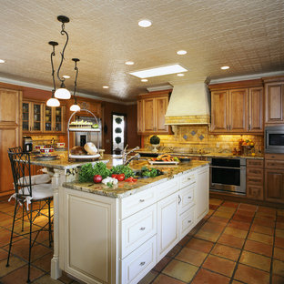 This is an example of a mediterranean u-shaped kitchen pantry in Orlando with an undermount sink, raised-panel cabinets, medium wood cabinets, granite benchtops, black splashback, stone tile splashback, white appliances, terra-cotta floors and with island.