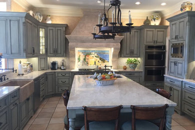 Huge tuscan u-shaped ceramic tile open concept kitchen photo in Other with a farmhouse sink, raised-panel cabinets, blue cabinets, quartzite countertops, beige backsplash, mosaic tile backsplash, stainless steel appliances and an island