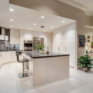 Inspiration for a mediterranean beige floor kitchen remodel in Other with flat-panel cabinets, white cabinets, stainless steel appliances, an island and black countertops