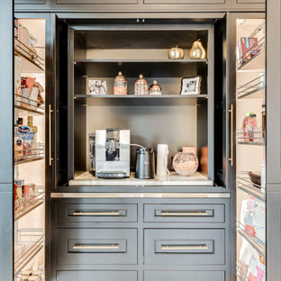 Idées déco pour une très grand cuisine américaine parallèle méditerranéenne avec un évier de ferme, un placard à porte affleurante, des portes de placard noires, un plan de travail en quartz modifié, une crédence beige, une crédence en marbre, un électroménager noir, un sol en marbre, un îlot central et un sol multicolore.