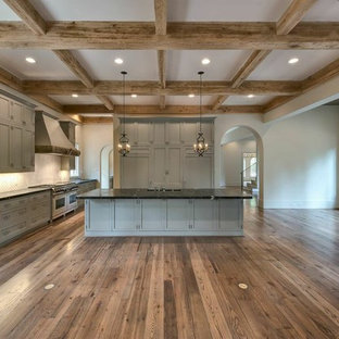 Large mediterranean open concept kitchen ideas - Large tuscan u-shaped medium tone wood floor open concept kitchen photo in Houston with a farmhouse sink, gray cabinets, soapstone countertops, white backsplash, paneled appliances and an island