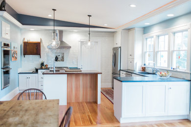 Eat-in kitchen - mid-sized transitional u-shaped light wood floor and brown floor eat-in kitchen idea in Boston with an undermount sink, shaker cabinets, white cabinets, soapstone countertops, white backsplash, subway tile backsplash, stainless steel appliances and an island