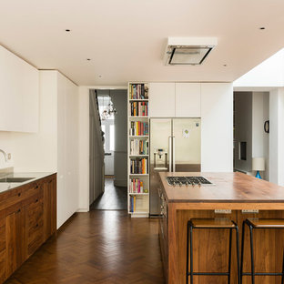 Inspiration for a medium sized contemporary u-shaped kitchen/diner in London with flat-panel cabinets, stainless steel appliances, medium hardwood flooring, an island, brown floors, an integrated sink, medium wood cabinets, wood worktops and brown worktops.