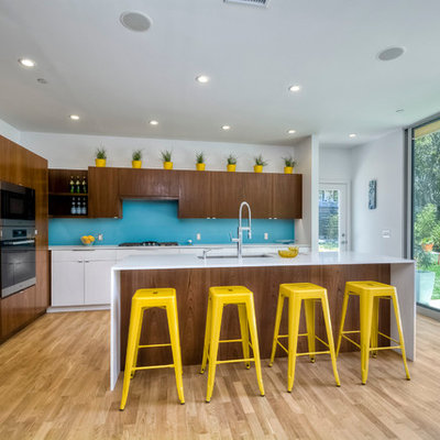 1960s galley light wood floor kitchen photo in San Diego with an undermount sink, flat-panel cabinets, dark wood cabinets, blue backsplash, glass sheet backsplash, stainless steel appliances and an island