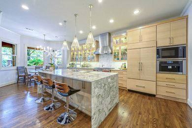 Eat-in kitchen - large transitional single-wall medium tone wood floor and brown floor eat-in kitchen idea in Dallas with a farmhouse sink, flat-panel cabinets, light wood cabinets, marble countertops, white backsplash, stainless steel appliances and an island