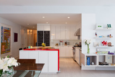 Mid-sized danish l-shaped light wood floor open concept kitchen photo in New York with an undermount sink, flat-panel cabinets, white cabinets, solid surface countertops, white backsplash, glass sheet backsplash, stainless steel appliances, an island and red countertops