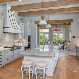 Traditional kitchen designs - Inspiration for a timeless galley medium tone wood floor kitchen remodel in Houston with an undermount sink, recessed-panel cabinets, gray cabinets, white backsplash, stone slab backsplash, stainless steel appliances and an island