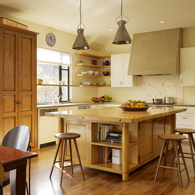 Example of a transitional enclosed kitchen design in San Francisco with recessed-panel cabinets, white cabinets, white backsplash, black appliances and wood countertops