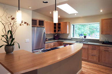 Inspiration for a mid-sized contemporary l-shaped medium tone wood floor open concept kitchen remodel in Seattle with an undermount sink, shaker cabinets, medium tone wood cabinets, wood countertops, green backsplash, stone slab backsplash, stainless steel appliances and an island