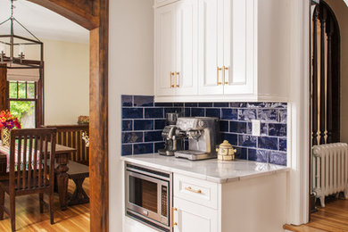 オマハにあるトランジショナルスタイルのおしゃれなキッチン (白いキャビネット、クオーツストーンカウンター、青いキッチンパネル、磁器タイルのキッチンパネル、シルバーの調理設備、淡色無垢フローリング、白いキッチンカウンター) の写真