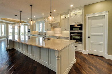 Inspiration for a huge transitional l-shaped brown floor and dark wood floor open concept kitchen remodel in Edmonton with an undermount sink, raised-panel cabinets, quartzite countertops, white backsplash, paneled appliances, an island, white cabinets and subway tile backsplash