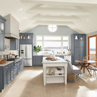 Large coastal eat-in kitchen remodeling - Example of a large beach style l-shaped beige floor and porcelain tile eat-in kitchen design in New York with an undermount sink, white backsplash, ceramic backsplash, stainless steel appliances, an island, white countertops, recessed-panel cabinets, gray cabinets and quartz countertops