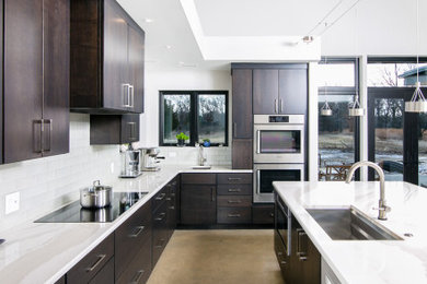 Eat-in kitchen - large modern l-shaped concrete floor eat-in kitchen idea in Detroit with an undermount sink, flat-panel cabinets, brown cabinets, quartzite countertops, white backsplash, glass tile backsplash, stainless steel appliances, an island and white countertops